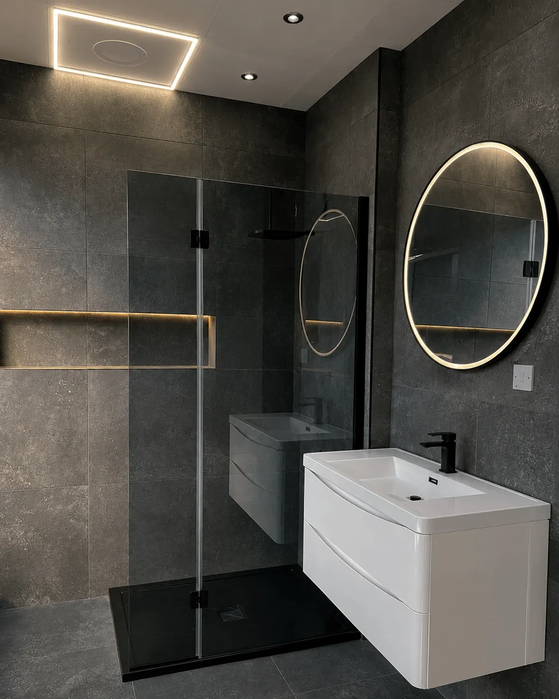 Grey shower room with a white floating vanity and round illuminated mirror