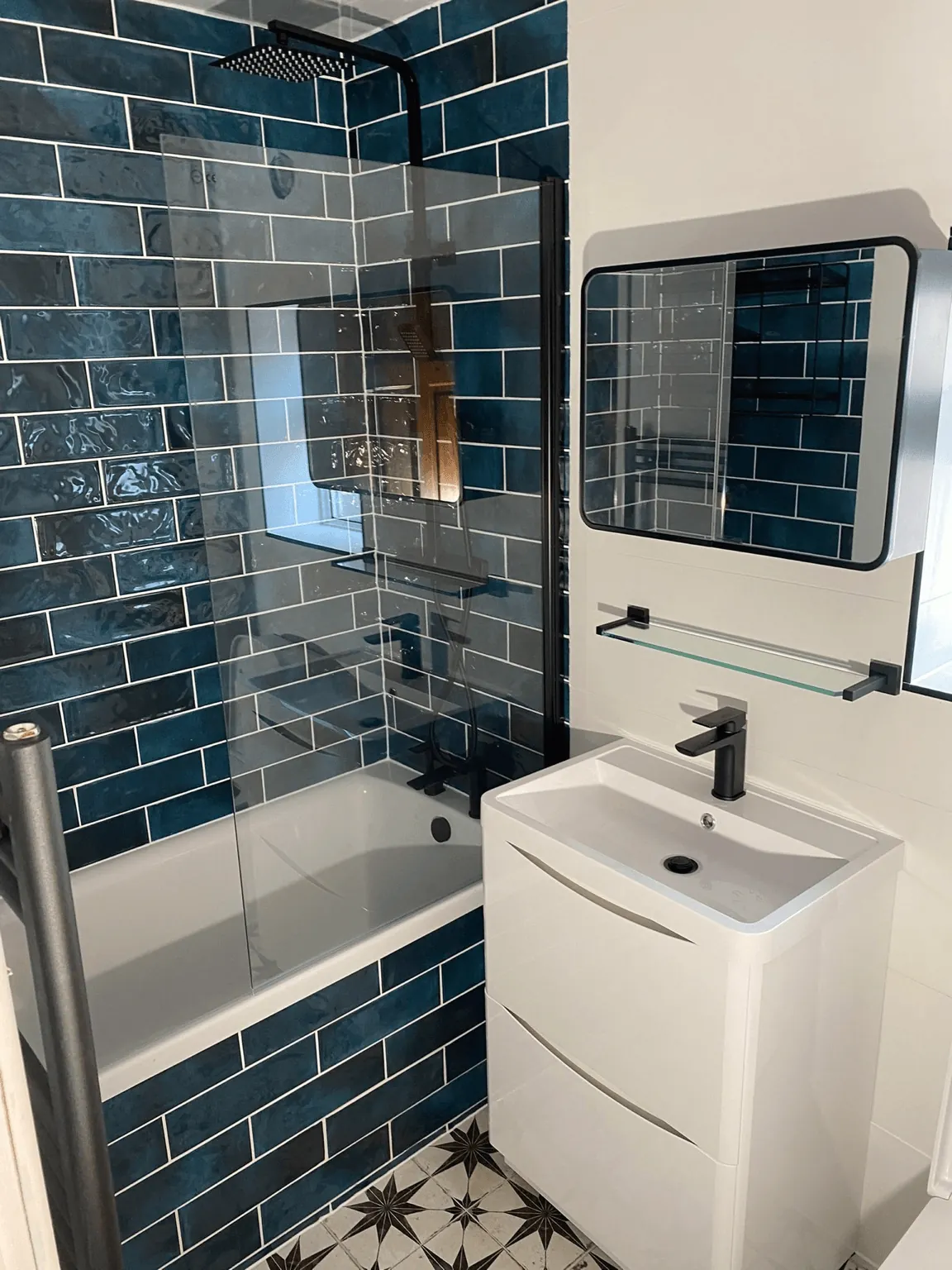 Bathroom with blue brick-pattern tiles, white vanity and bath screen