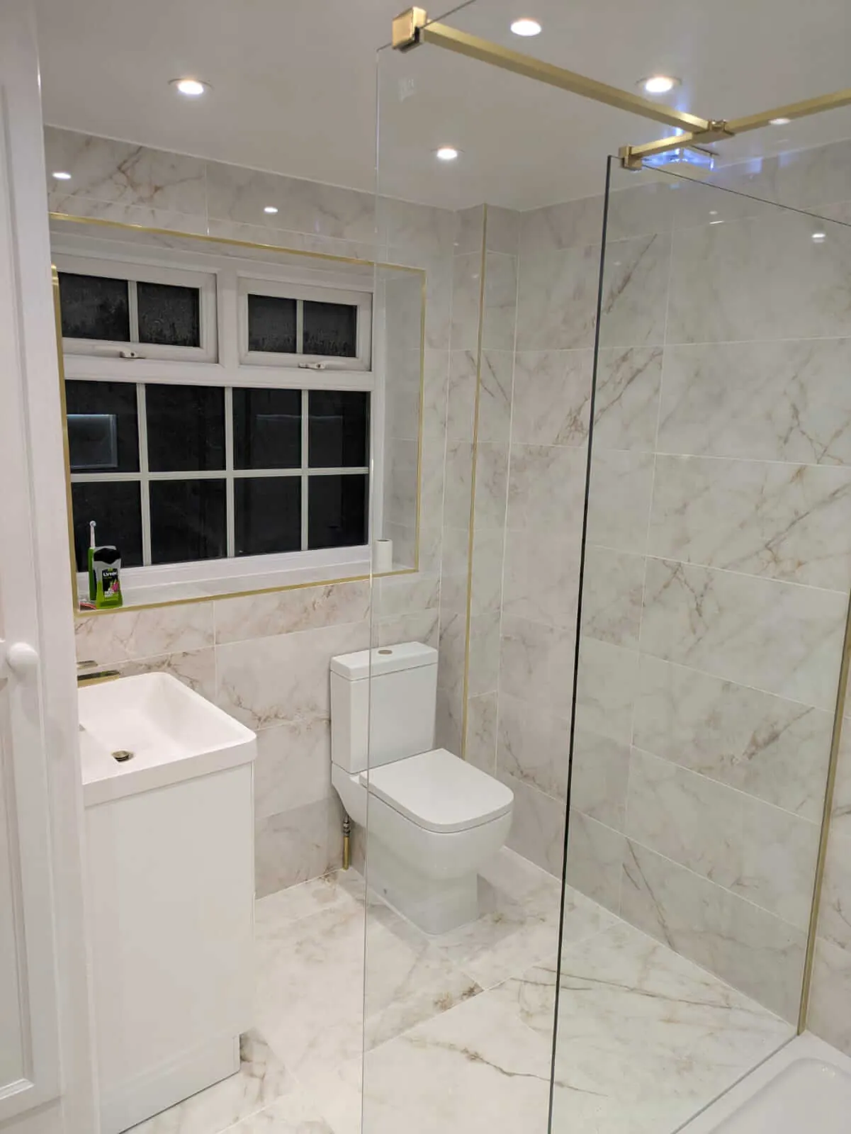 Marble-effect shower room with white fittings and gold-coloured trim