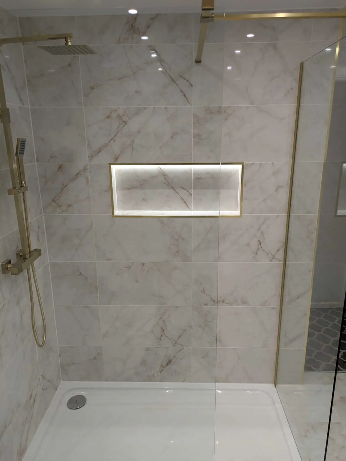 Marble-effect shower enclosure with gold-coloured trim and recessed shelf