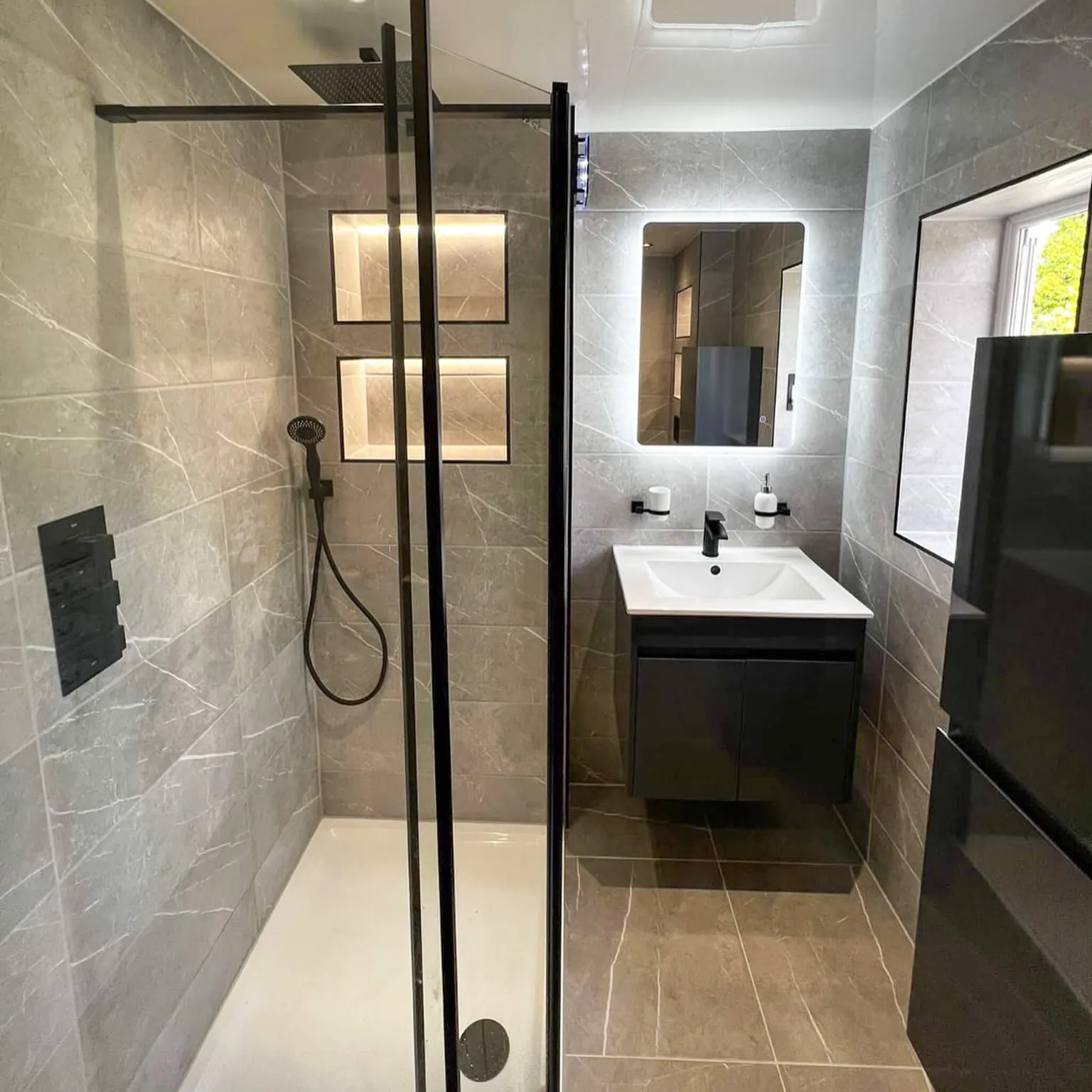 Ensuite with a black-framed shower, recessed shelves and wall-mounted vanity