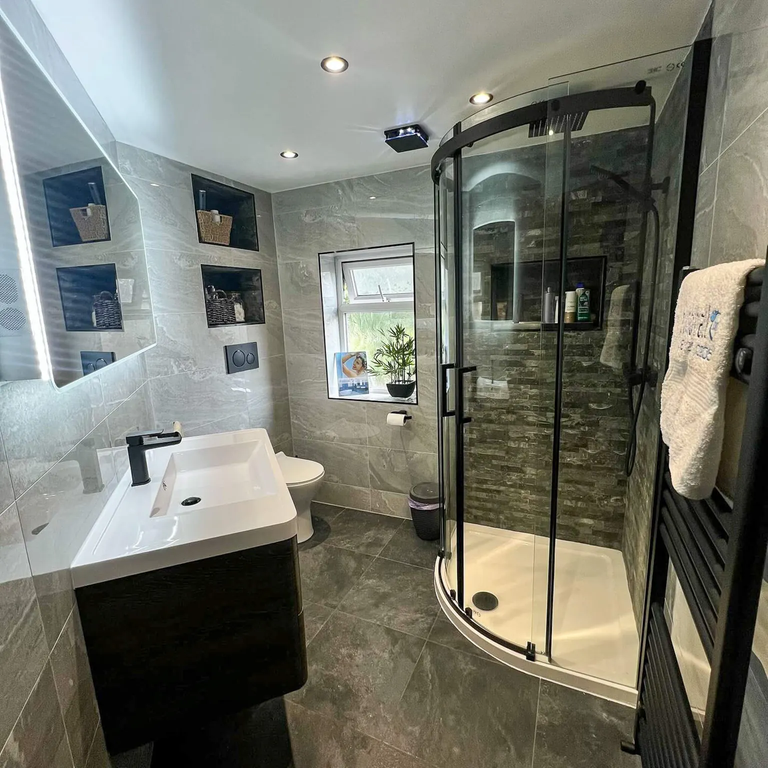 Ensuite with a curved black-framed shower enclosure and fitted vanity