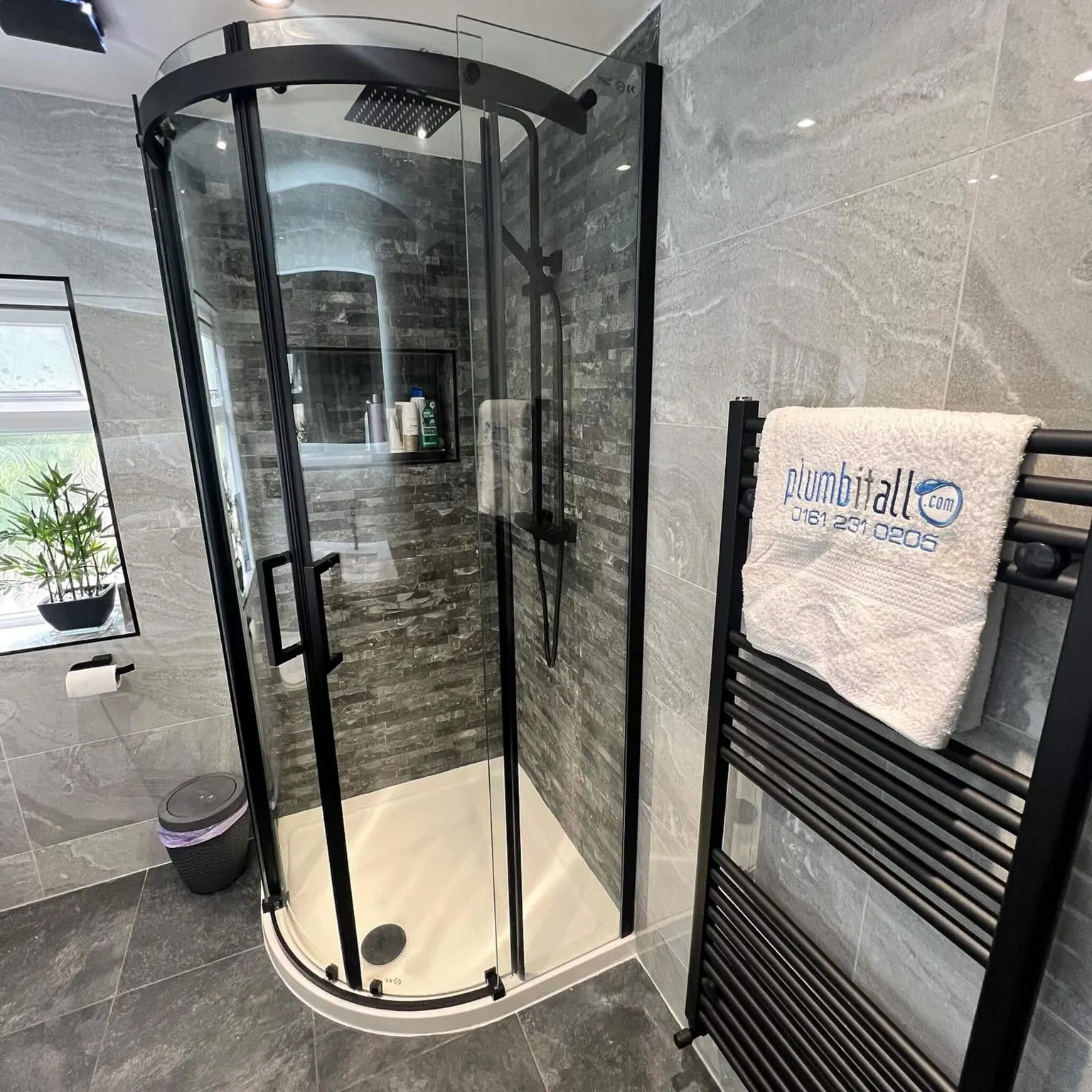 Curved ensuite shower enclosure beside a black towel radiator