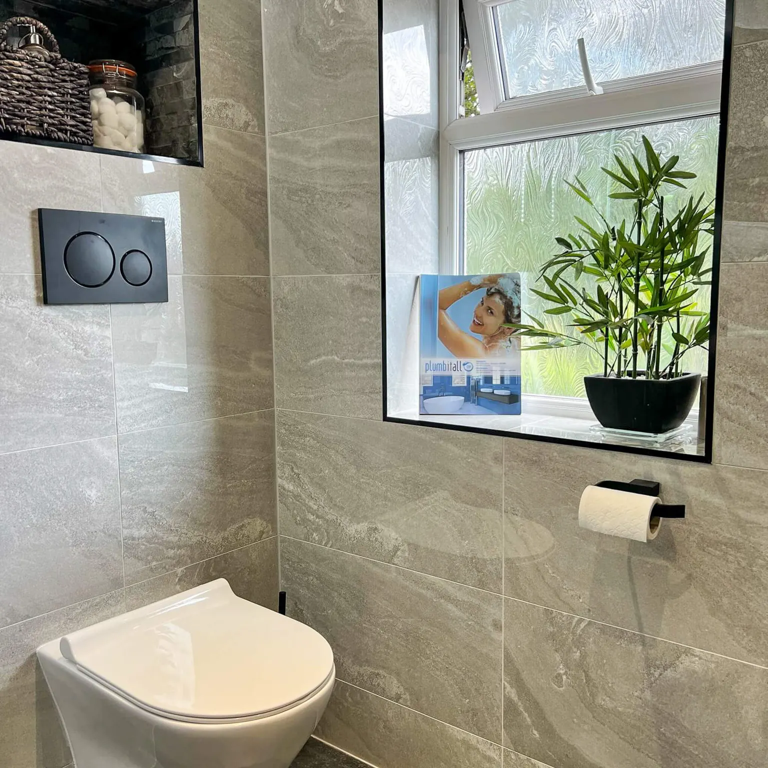 Grey tiled ensuite with a wall-hung toilet and recessed storage shelves