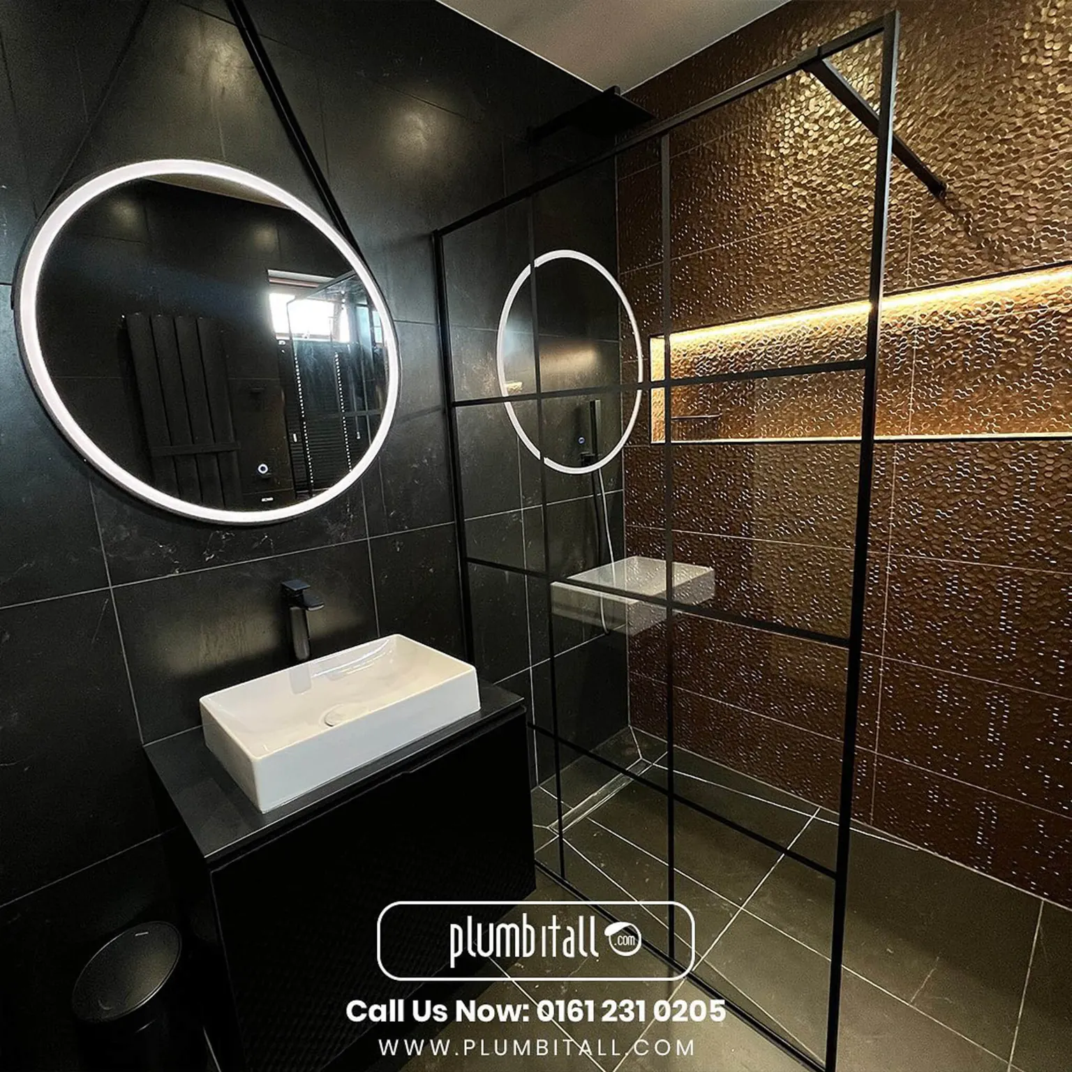 Dark tiled wet room with a black-framed shower screen and circular illuminated mirror