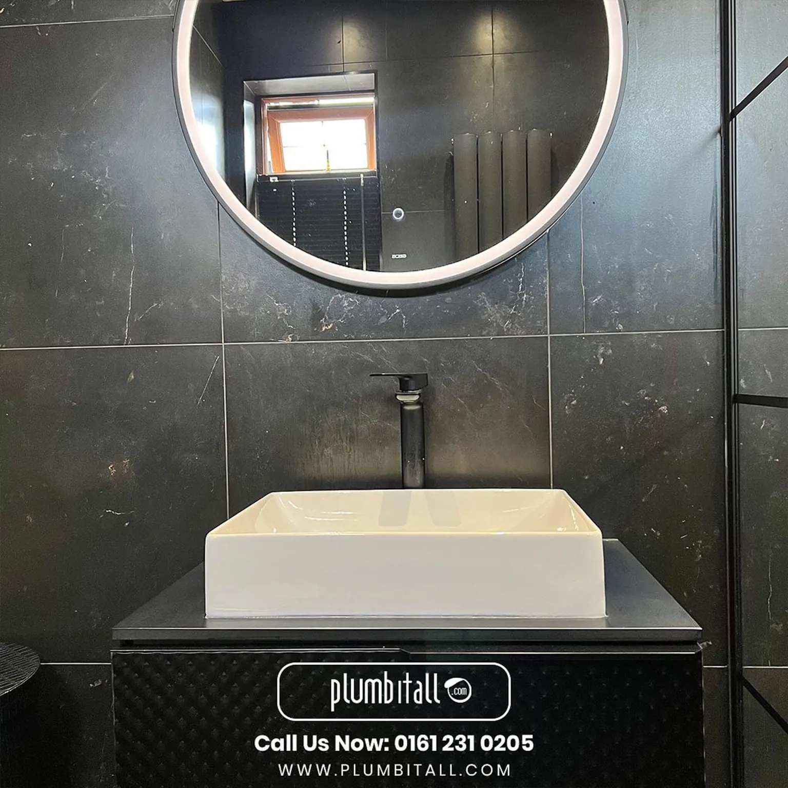 Rectangular countertop basin with a black tap and round illuminated mirror
