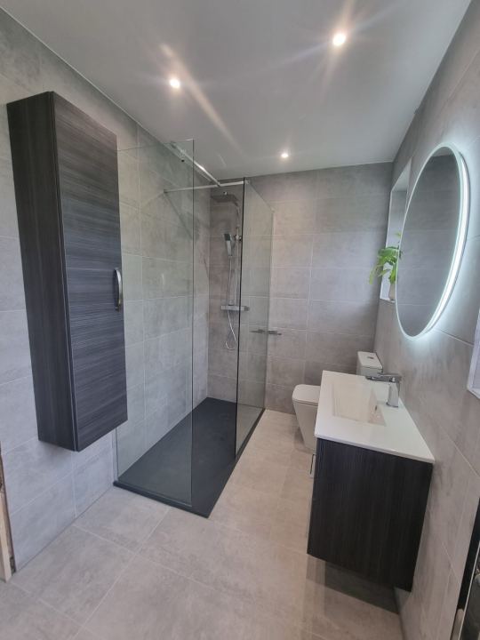 Grey-tiled bathroom in Cheadle with a walk-in shower and illuminated round mirror